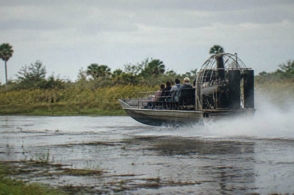 an airboat moving fast across open water with spray trailing behind