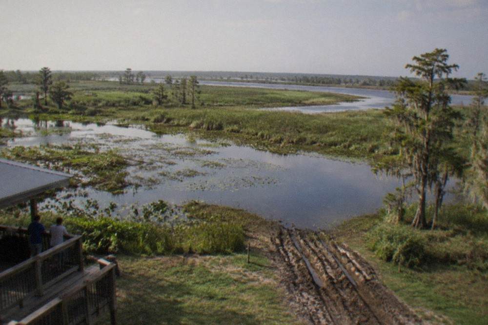 Wide Florida wetland with grassy islands and a channel of open water under a hazy sky