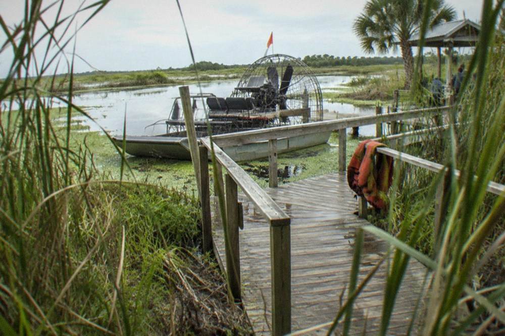Airboat dock at the edge of a reedy marsh with a boarded walkway leading to the water
