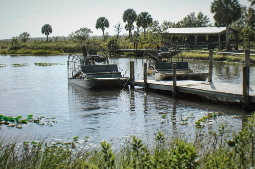 Two airboats tied at a dock on a shallow Kissimmee lake