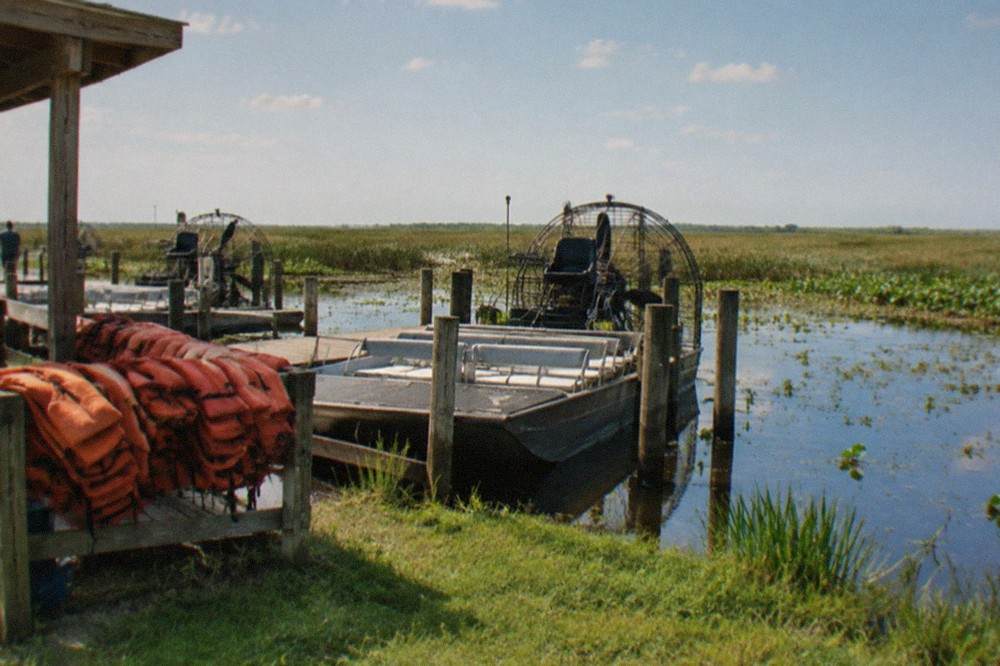 An airboat dock on a grassy lakeshore with sawgrass marsh stretching to the horizon