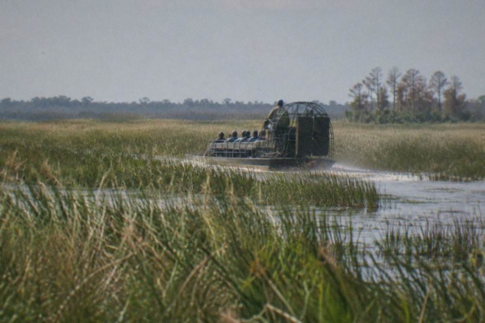 Airboat cruising through tall marsh grass on a wide Florida lake