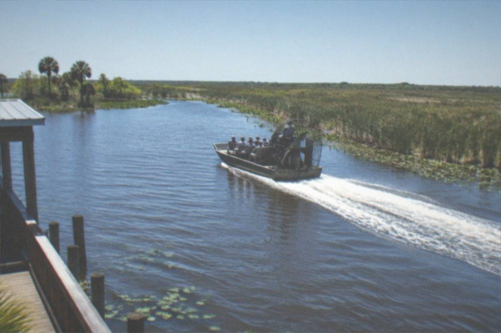 Airboat cutting a wake across open water under a clear sky