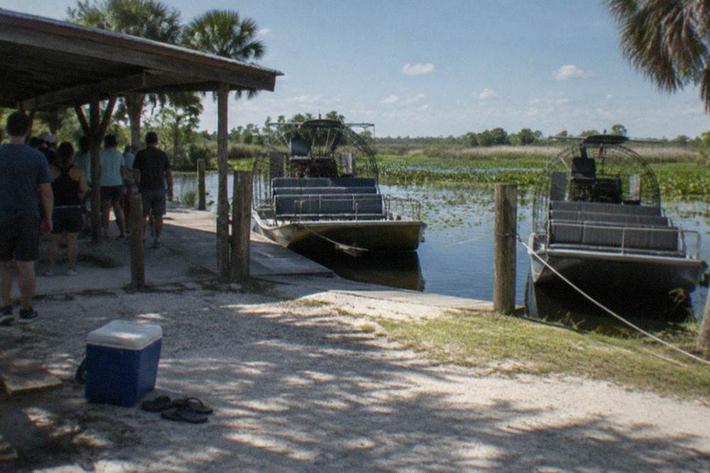 Airboat dock with parked boats and visitors waiting in line
