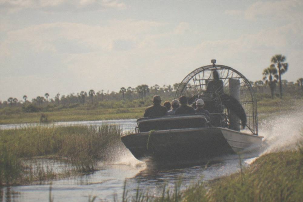 Airboat at speed crossing a wide grass marsh