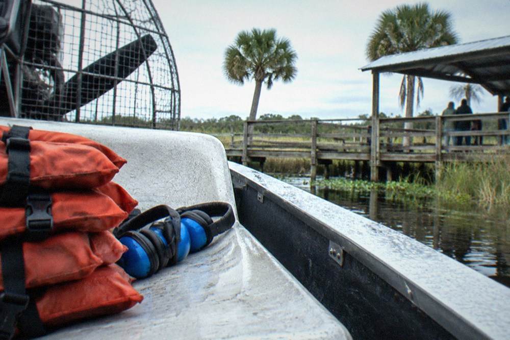 Stacked life jackets and ear protection headsets on an airboat seat before departure