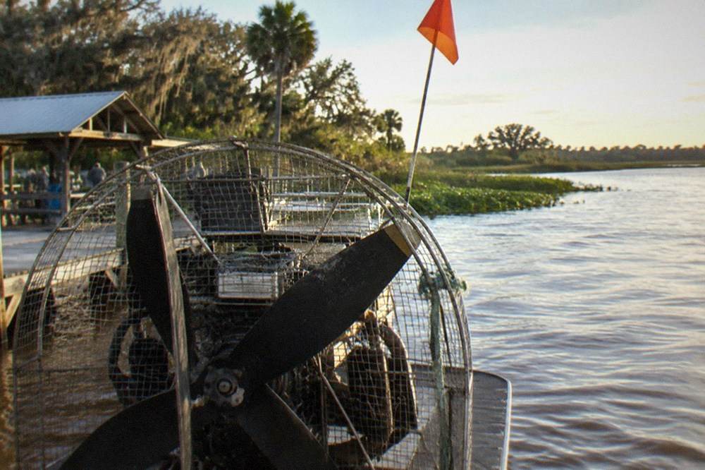 Airboat engine and propeller cage seen from behind, orange safety flag on a tall mast