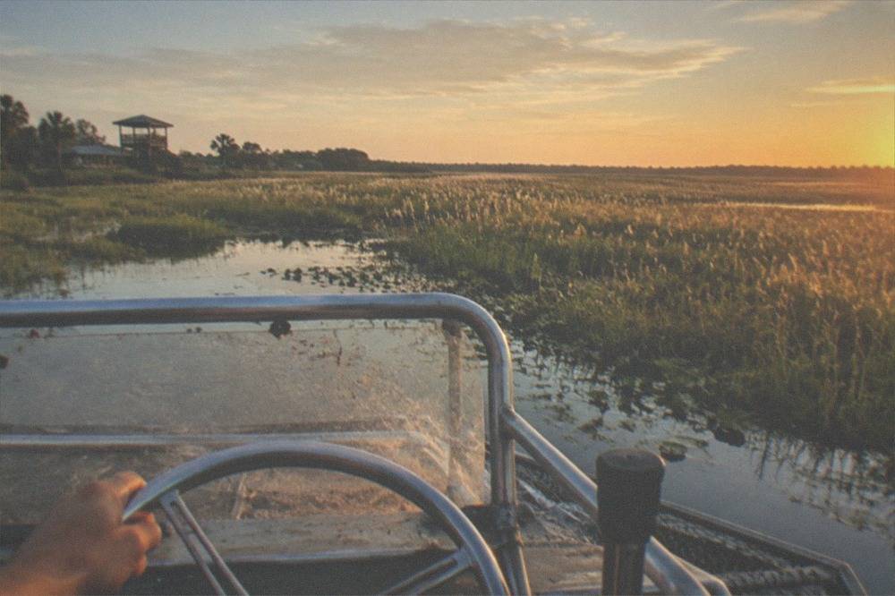 Open marsh vista seen from the raised helm of an airboat at golden hour