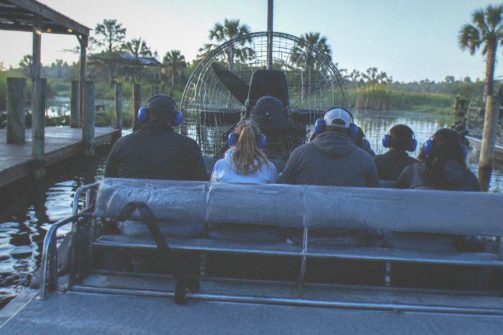 Passengers in matching ear protection seated on an airboat bench before departure