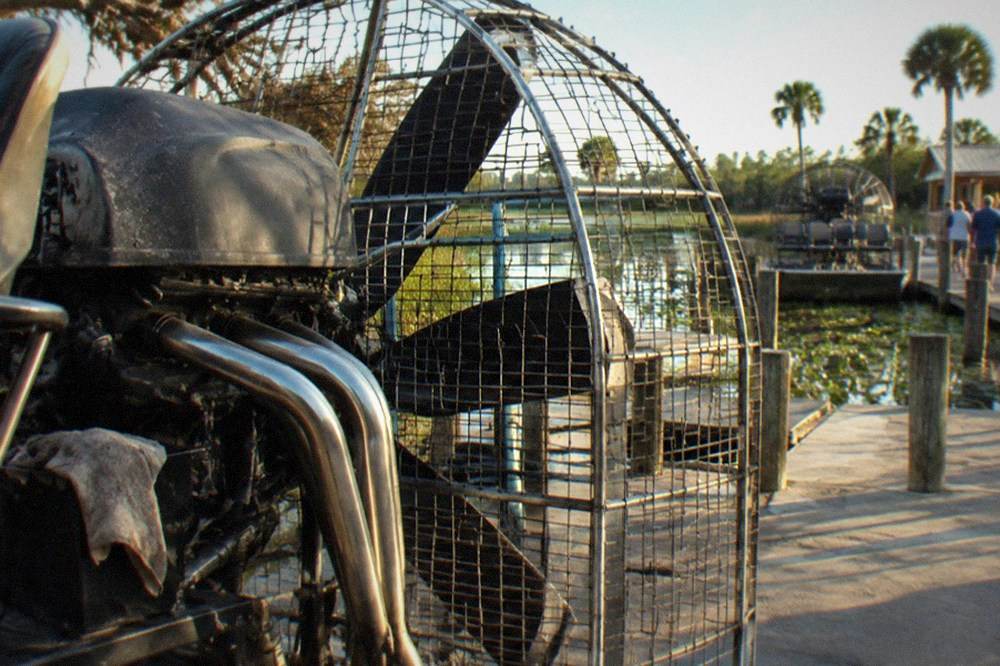 A close view of an airboat's propeller cage and engine at the dock