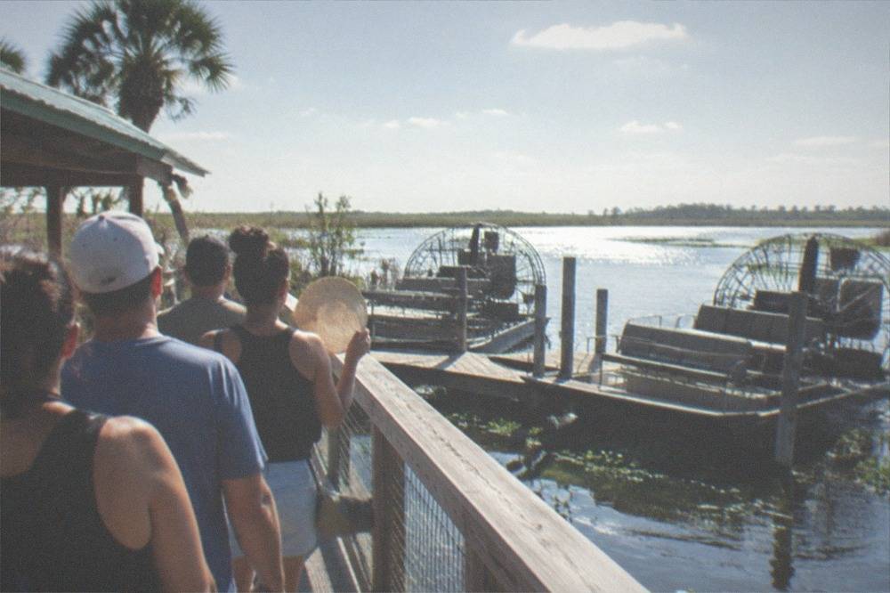 Passengers in a line at a lakeside airboat dock waiting to board