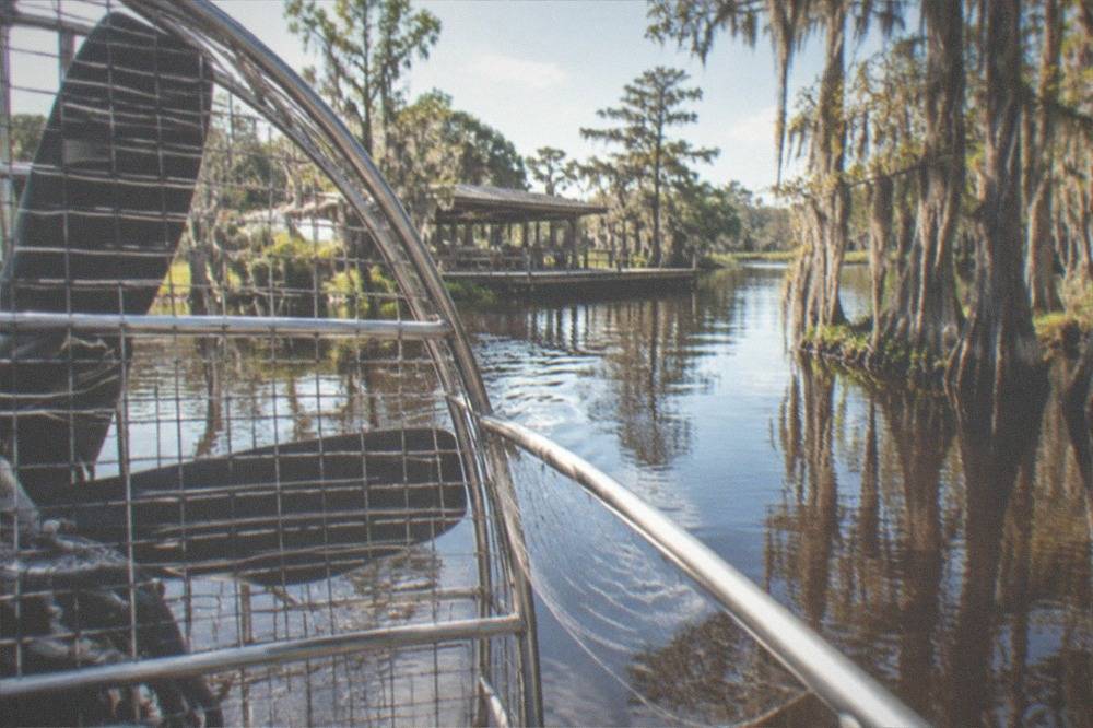 A close view of an airboat propeller cage above calm water