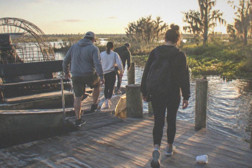 Small group of passengers climbing down from an airboat at the dock
