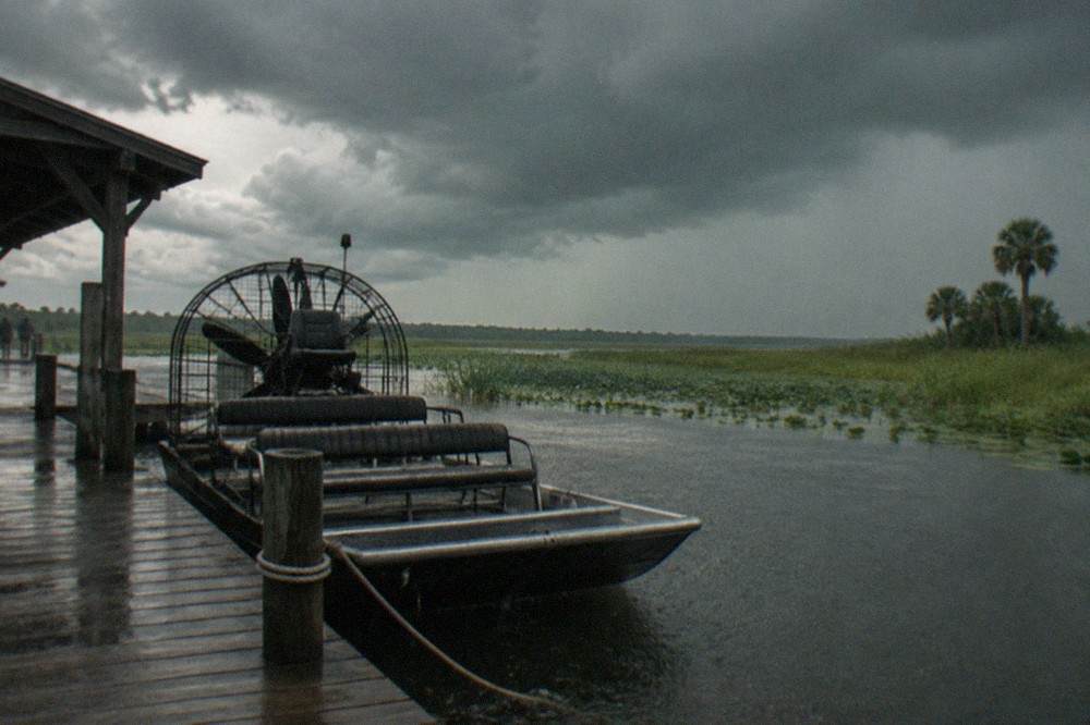 Airboat resting on a dock with dark storm clouds building over a Florida marsh