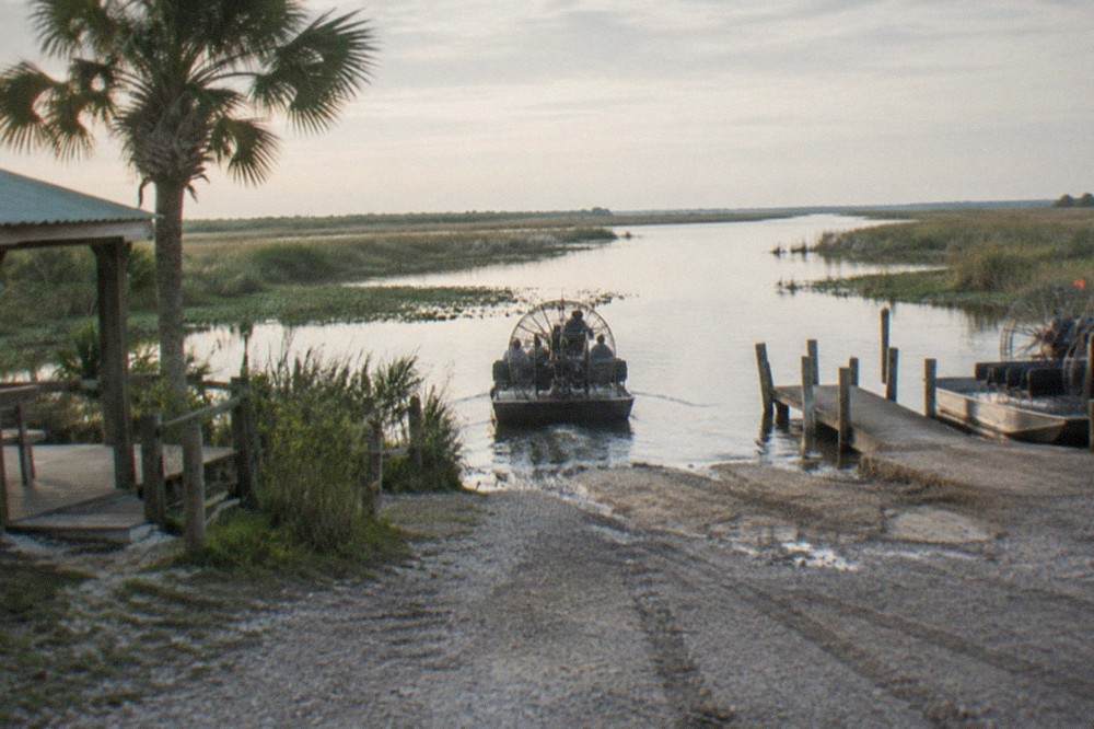 Airboat dock at a marsh launch area with flat grassland and open water stretching to the horizon