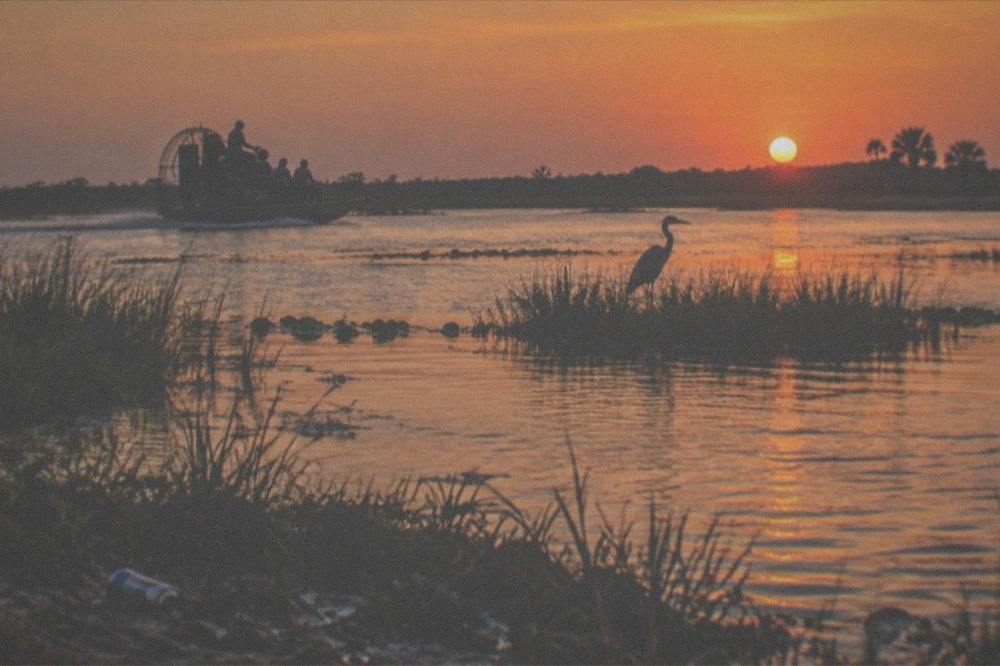Open expanse of shallow lake water with grass islands and a wide horizon at sunset