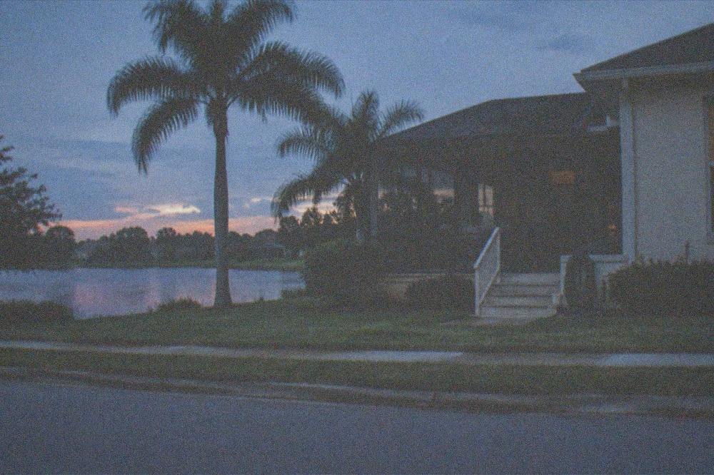 Vacation home porch overlooking a small lake at dusk with palm trees