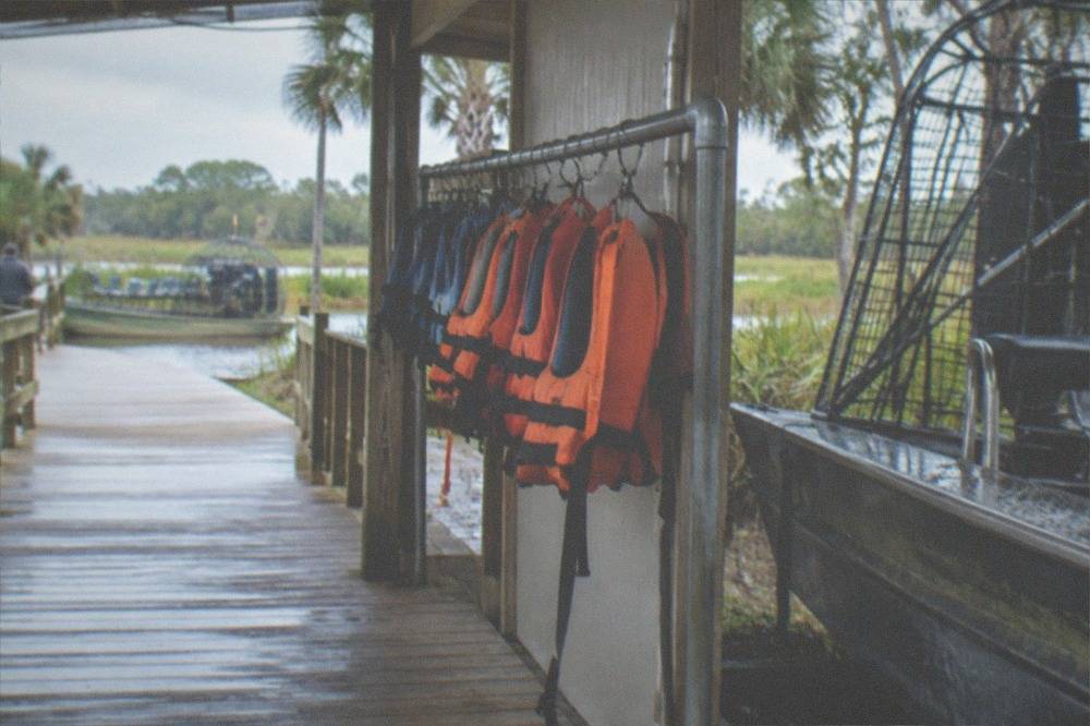 Dock area with life vests hanging on a rack beside an airboat boarding ramp